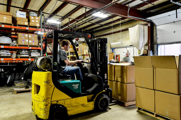 A forklift being used to move multiple boxes of aircraft brakes and wheels