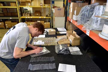An employee diligently packs small aircraft parts into boxes