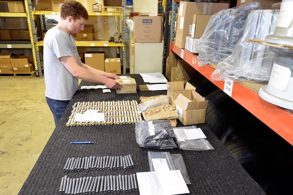 An employee organizes small aircraft parts into boxes